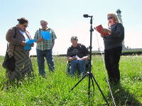 4 people in a field with a microphone and scripts