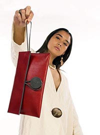 A lady holding a red leather purse in the air.