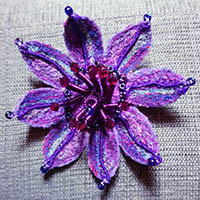 Embroidered purple flower with red bead stamen.