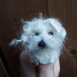 Dog finger puppet, made from white felt.